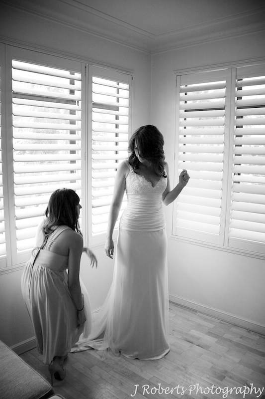 Bride having her dress laid out by bridesmaid - wedding photography sydney